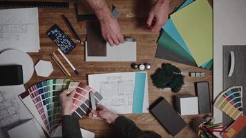 Design and architecture studio. Close-up, male and female hands of interior designers working with samples of materials and color palettes. Working on an apartment project video