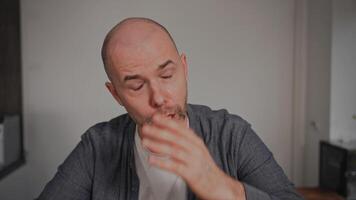 A middle-aged man sits at home, visibly crying and looking deeply sad. He appears to be struggling with problems and depression, conveying a powerful sense of sorrow and despair in an intimate video