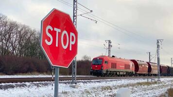 siauliai, Lituânia - 19 novembro, 2024- carga trem passeio em estrada de ferro velozes passar carros em pé de trilhos Pare placa dentro frio inverno dia dentro báltico país Lituânia. eu importar exportação bens conceito video