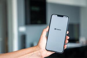 Prague, Czech republic - May 2, 2024. Woman holding iPhone with logo of application CapCut on the screen, using mobile application for business home. High quality photo