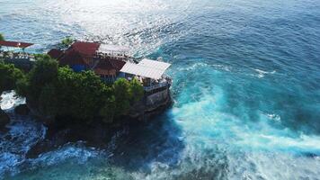 Scenic landscape with rocks on coastline and blue ocean with waves in Lembongan island, Bali. Aerial view video