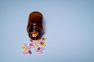 An array of colorful medication capsules and pills spills from an amber glass bottle, highlighting importance of pharmaceutical safety and responsible medication storage photo