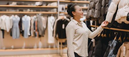 Woman smiles as she browses for jackets in stylish clothing store, indicating delightful shopping experience amidst variety of fashionable attire photo