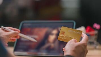 People shopping online using tablet concept. Close-up of person holding gold credit card and digital pen, ready to engage in online shopping on tablet in cozy environment photo
