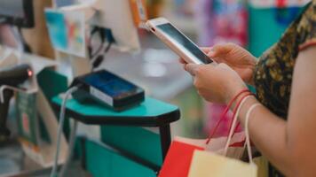 Shopper uses smartphone for payment at checkout counter, convenience of digital transactions in everyday shopping photo