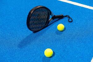 paddle tennis racket and balls on the blue paddle court photo