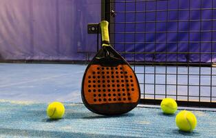 padel racket and yellow balls placed on court near net photo