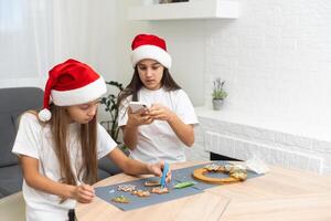 Two girls sisters are playing around in the kitchen after making Christmas cookies, they draw with flour on the table and on their faces. Christmas, New Year concept photo