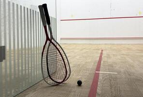 Two rackets and two squash balls lie on the parquet floor. photo