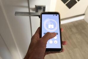 smart house, home automation, device with app icons. Man uses his smartphone with smarthome security app to unlock the door of his house. photo