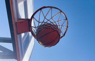 Basketball scoring a basket as it goes through the hoop and making a swish in the net photo