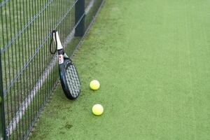 Paddle tennis racket, ball and net on the grass photo