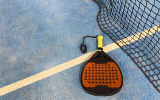 padel racket and yellow balls placed on court near net photo