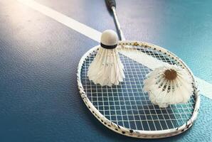Cream white badminton shuttlecock and racket with neon light shading on floor in indoor badminton court, copy space, soft and selective focus. photo