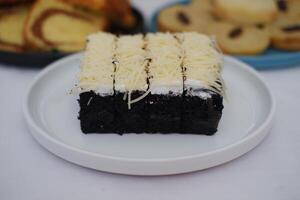 A piece of black cake topped with shredded cheese photo