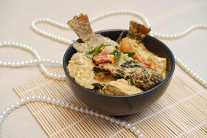 Fried fish with curry in a bowl on a wooden table. photo