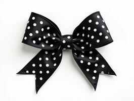 Black ribbon bow with white polka dots isolated on a white background. Decorative accessory for gifts, crafts, and festive designs photo