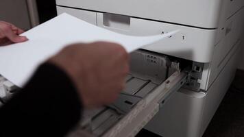 Office worker putting a stack of paper A3 into the printer tray video