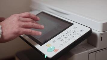 An office worker makes print settings for a printer on a touch screen video