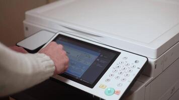 An office worker makes print settings for a printer on a touch screen video