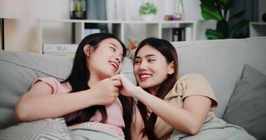 Handheld low angle view shot, Lesbian couple talking and sharing moments of love and happiness together on the sofa in the living room at home. LGBTQ Lifestyle. video