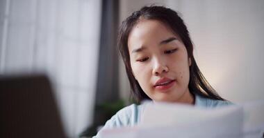 Footage of handheld, Female freelancer holding document explaining project in online meeting with team members via laptop in home office. Working from home, Remote working. video