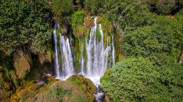 Aerial view of a small waterfall in the uncontaminated nature. Water, rocks and trees in a natural scenary. photo