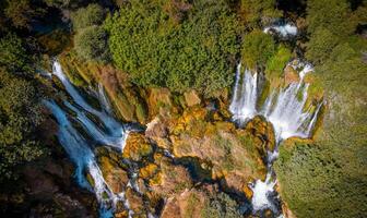 Aerial view of a small waterfall in the uncontaminated nature. Water, rocks and trees in a natural scenary. photo