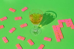 Pink dominoes with alcoholic beverage on green background. Drink and board game concept. Green and pink trend colors. Colorful domino layout. photo