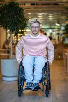 Confident disabled young man on wheelchair in cafe with adaptive accessible place for handicapped. photo