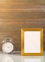 Picture mock up with golden frame and alarm clock photo