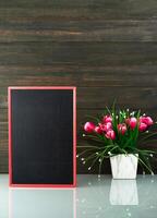 Flower vase and blank chalkboard on table photo