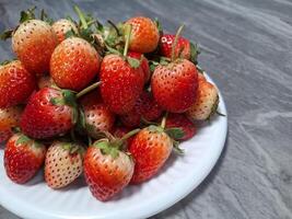 Blurred image of strawberries on a white plate placed on a table. photo