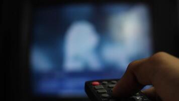 close-up of a man's hand holding a TV remote control. a man's finger pressing the buttons on an analog TV remote control using set top box video