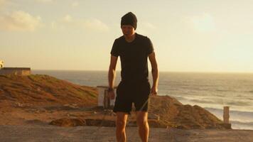 Active sporty man jumping while training with elastic ropes by sea video