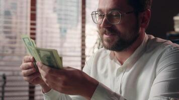 Joyful Caucasian businessman guy trader executive boss counting money savings banknotes in office worker smile accountant male calculate company profit business man dollars cash wages salary earnings video