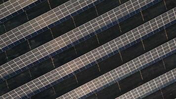 Top down panning view man worker working at solar power station drive tractor in row of solar panels. A worker on a garden tractor mows grass on solar panel farm video