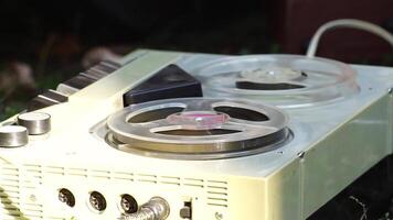 Reel to reel tape recorder playing. Rotating vintage music player close up. Retro tape. Spinning reels metallic color with red disc. View from above. Popular Disco Trends video