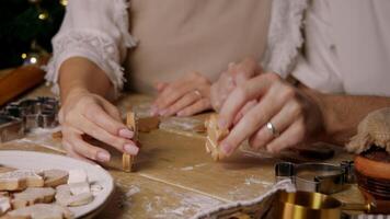 Couple in love are having fun and playing around at a festive Christmas table, using gingerbread men cookies. video