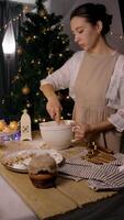 A young woman is mixing dough ingredients with a whisk, surrounded by a festive New Year and Christmas atmosphere. Vertical. video