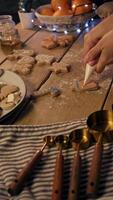 Housewife in kitchen with the help of improvised means creates unique festive atmospheric pattern on ginger cookies with help of multi-colored glaze video