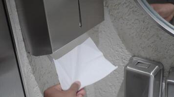 Hand Using Paper Towel Dispenser in a Hygienic Public Restroom with Clean White Tiles video