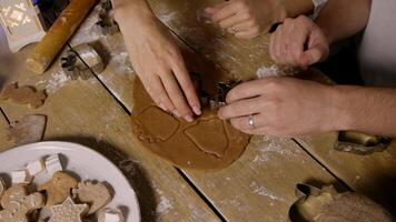 Husband and wife are cooking Christmas cookies together. They cutting out ginger cookies from piece of dough using molds. Top view. video