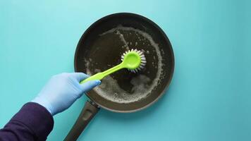Cleaning a Pan with Gloves and Brush on a Colorful Background video