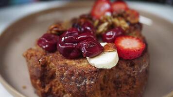 Enjoy a Delicious Serving of French Toast Garnished with Fresh Berries and Nuts video