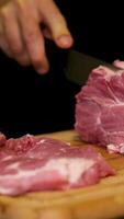 A butcher cuts a large piece of selected meat with a knife on wooden board. Selected pork. video