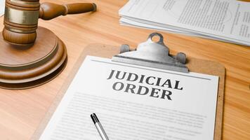 Wooden Lawyer Desk with Highlighted Word 'JUDICIAL ORDER' on Clipboards Documents on Table. Judge's Wooden Gavel Knocking and Court Making Decision on 'JUDICIAL ORDER' in Courtroom. video