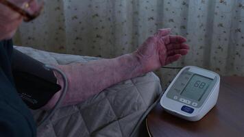 Elderly person's hand operating home blood pressure monitor. Accessible technology enabling self-care and self-monitoring of wellness metrics video