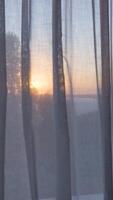 A view of the sunset through a window with curtains video
