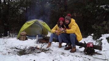Girl and guy with phone near campfire in winter forest video